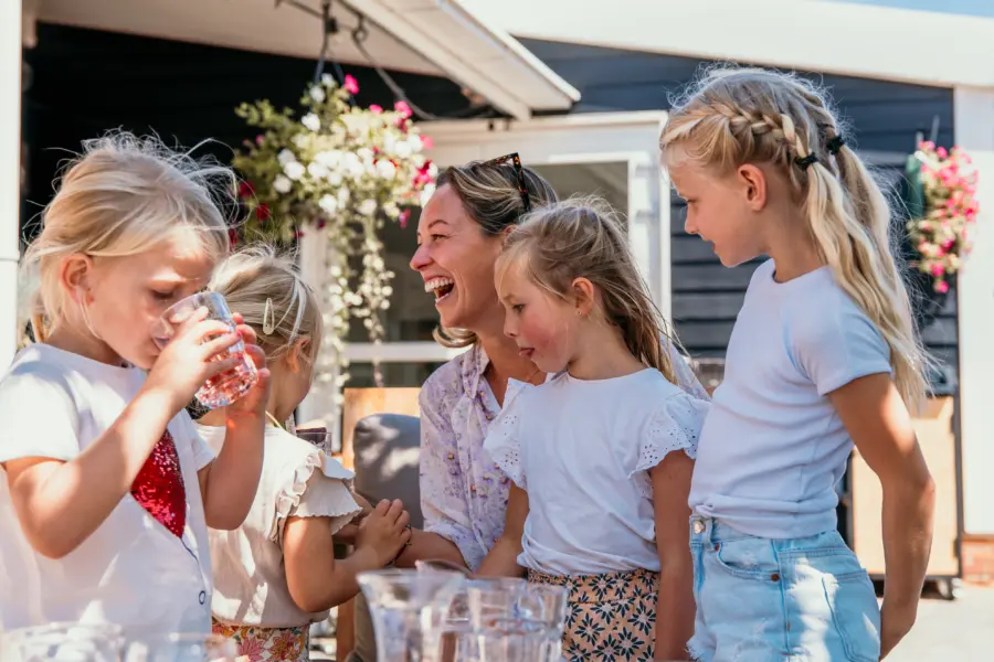 Spelende kinderen, een moeder die hardop lacht en frisse drankjes op tafel. Pure zomerse gezelligheid bij Strandpark De Zeeuwse Kust