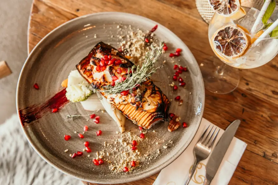 Gegrilde pompoen met granaatappel en kruiden stijlvol gepresenteerd in het restaurant van Strandpark De Zeeuwse Kust op een sfeervol gedekte tafel